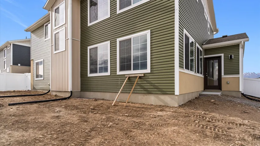 Two-story residence featuring green horizontal siding and tan stucco accents