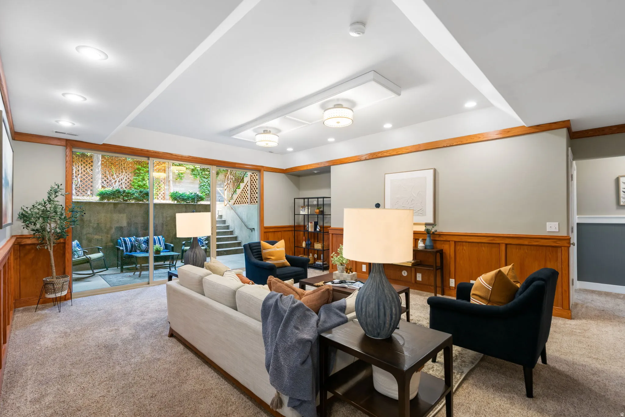 Lower level also has high ceilings, the family room has architectural paneling, large sliding glass door for natural light and opens onto a covered patio for indoor outdoor living.