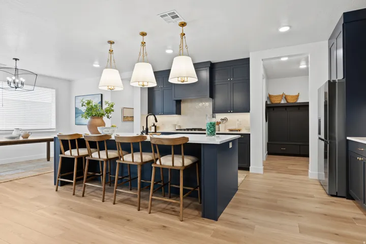Gourmet kitchen featuring a large island with seating, dark blue cabinetry, light wood-finish flooring, and stainless steel appliances