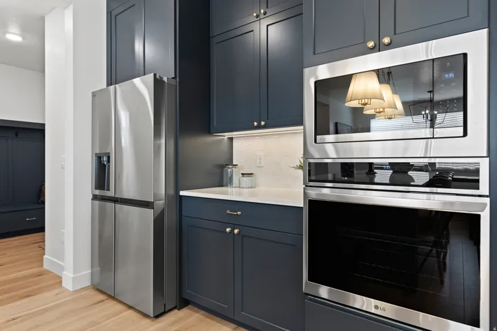 Kitchen featuring dark blue cabinetry, stainless steel appliances, light wood-finish flooring, and white countertops