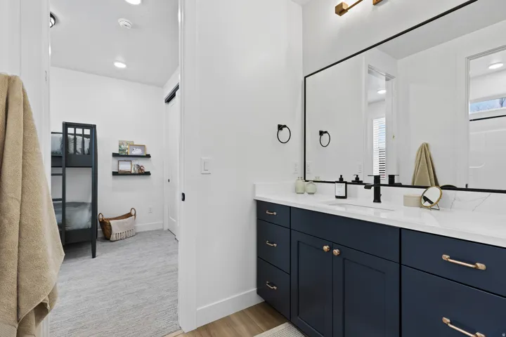 Bathroom vanity featuring a quartz countertop, integrated sink, and dark blue cabinetry with gold-tone hardware