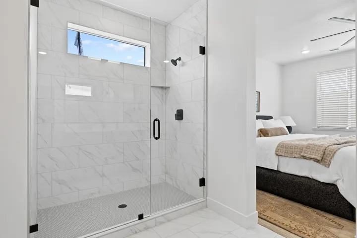 Glass-enclosed shower featuring large format wall tiles, a mosaic tile floor, and matte black fixtures