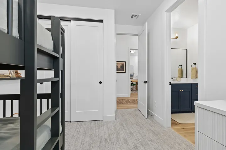 Carpeted room featuring a dark-colored bunk bed, white doors, and a hallway entrance