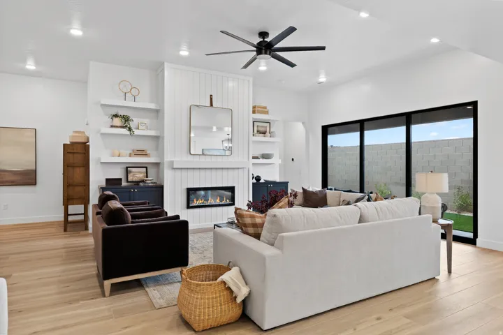 Spacious living area featuring light wood-finish flooring and a central fireplace with shiplap-style surround