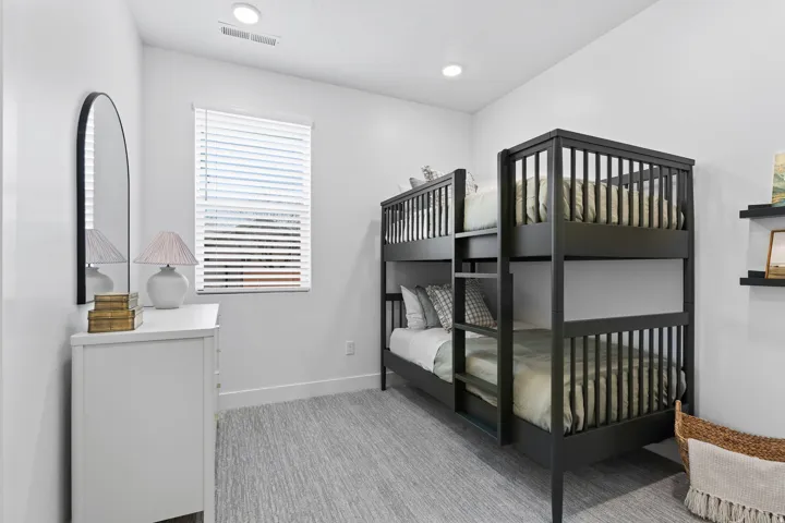 Spacious room with light gray wall-to-wall carpeting, white walls, and a large window with blinds