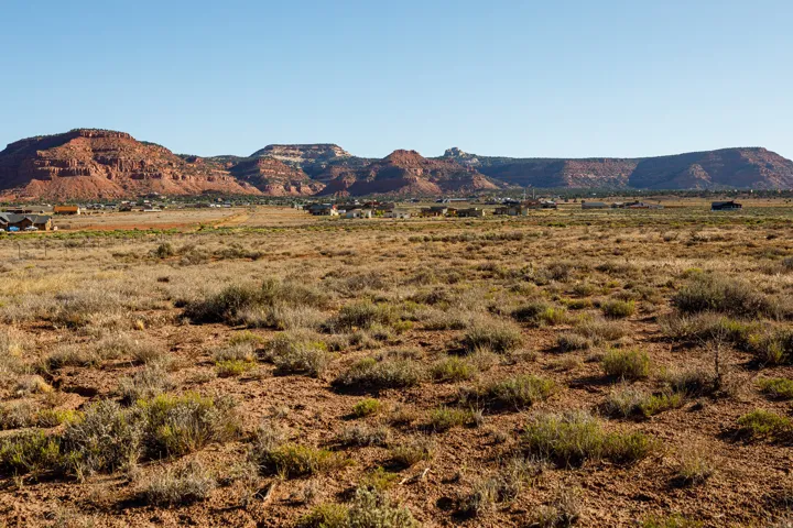 Expansive desert landscape with scattered brush and red rock formations