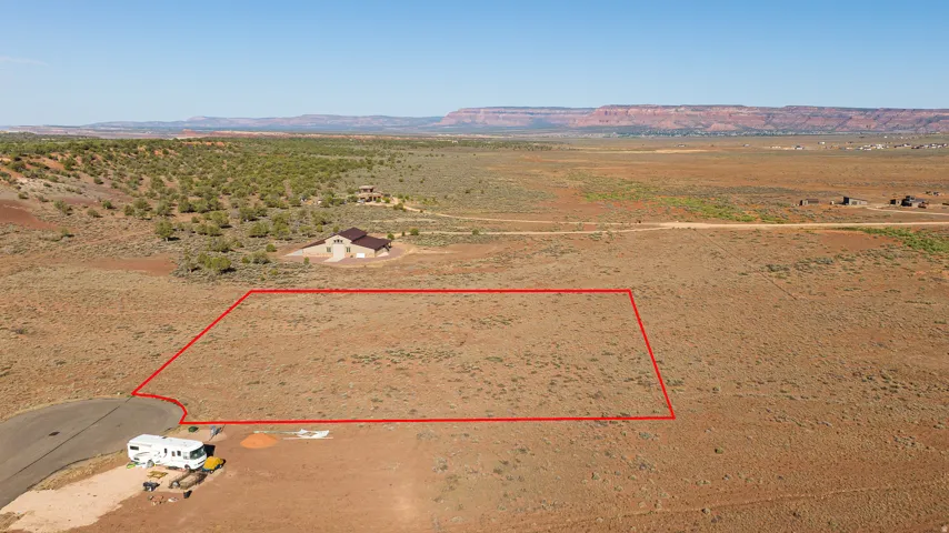 Expansive desert lot featuring a clear building envelope, established road access, and distant mesa formations