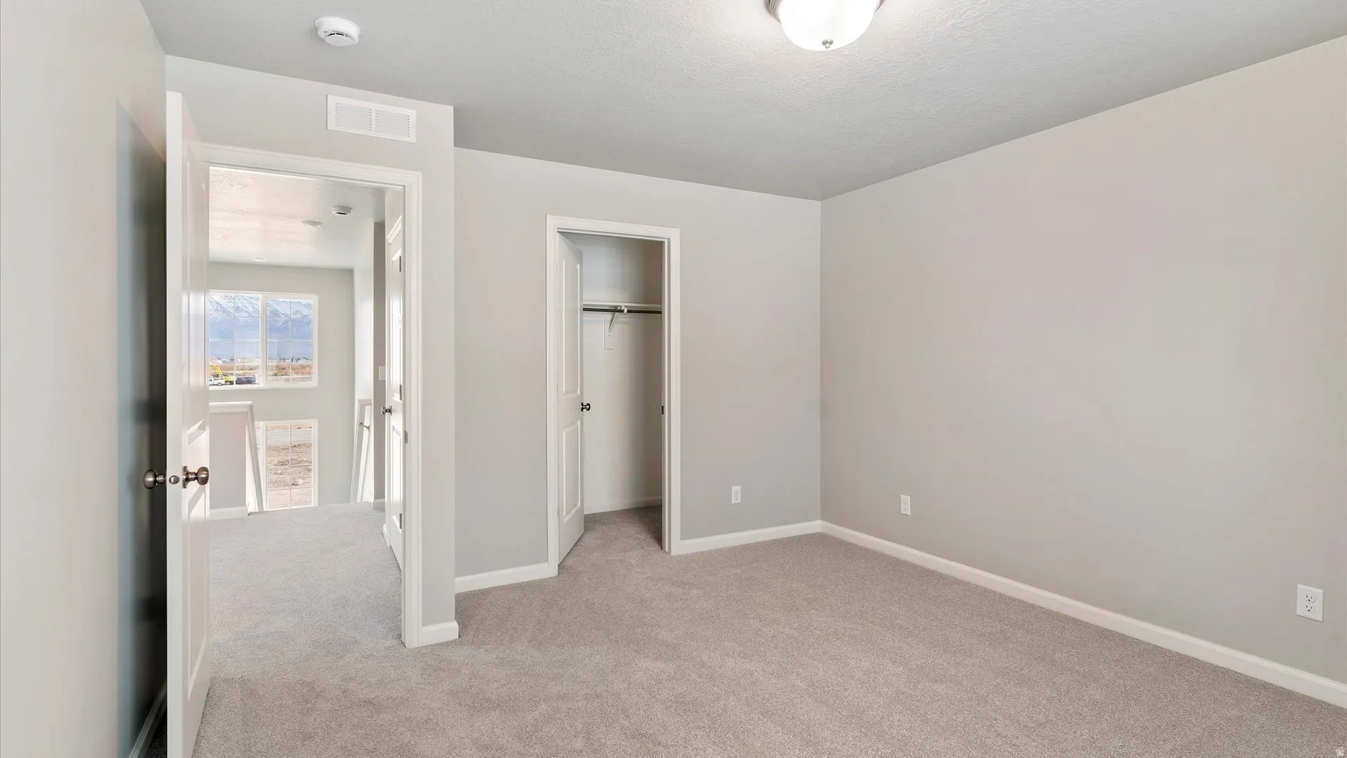 Carpeted room featuring a ceiling-mounted light fixture, white baseboards, and neutral wall paint