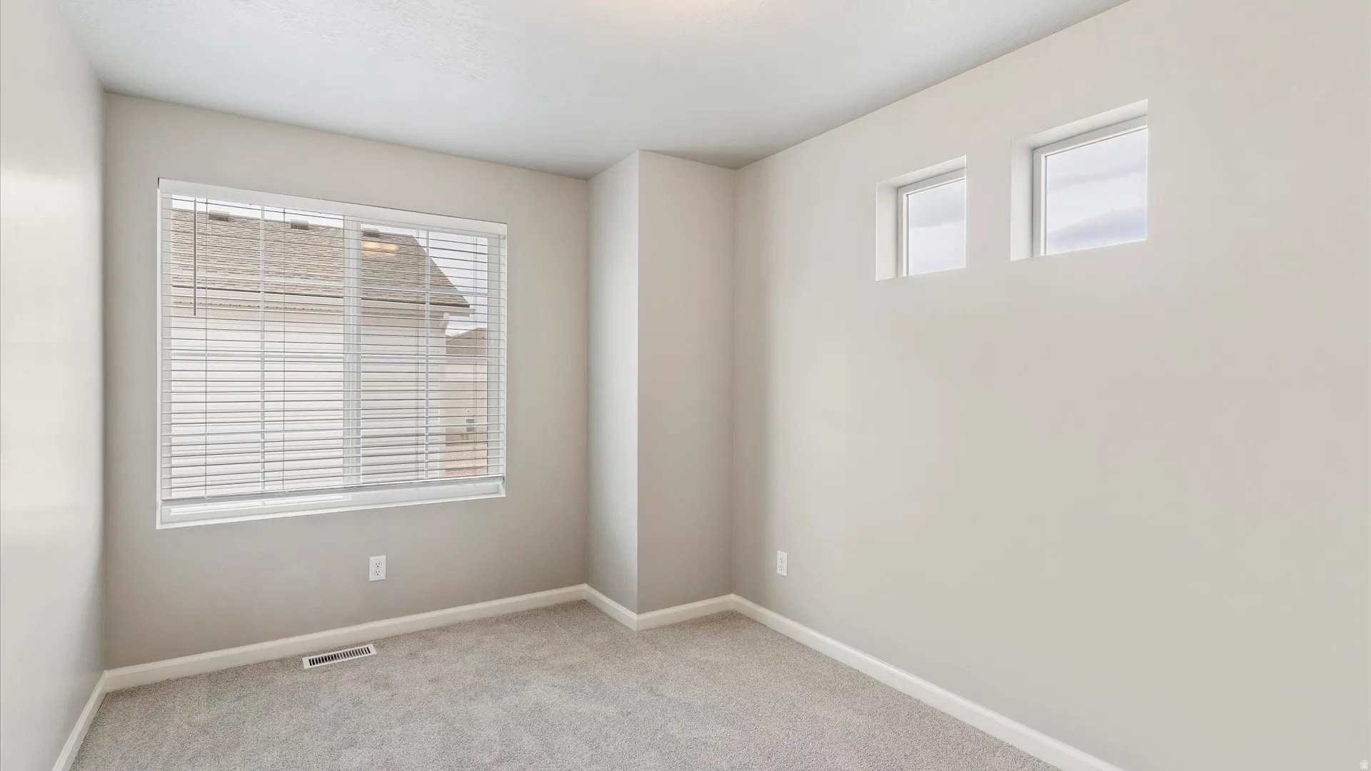 Neutral-toned room featuring a large window with blinds and two high transom windows