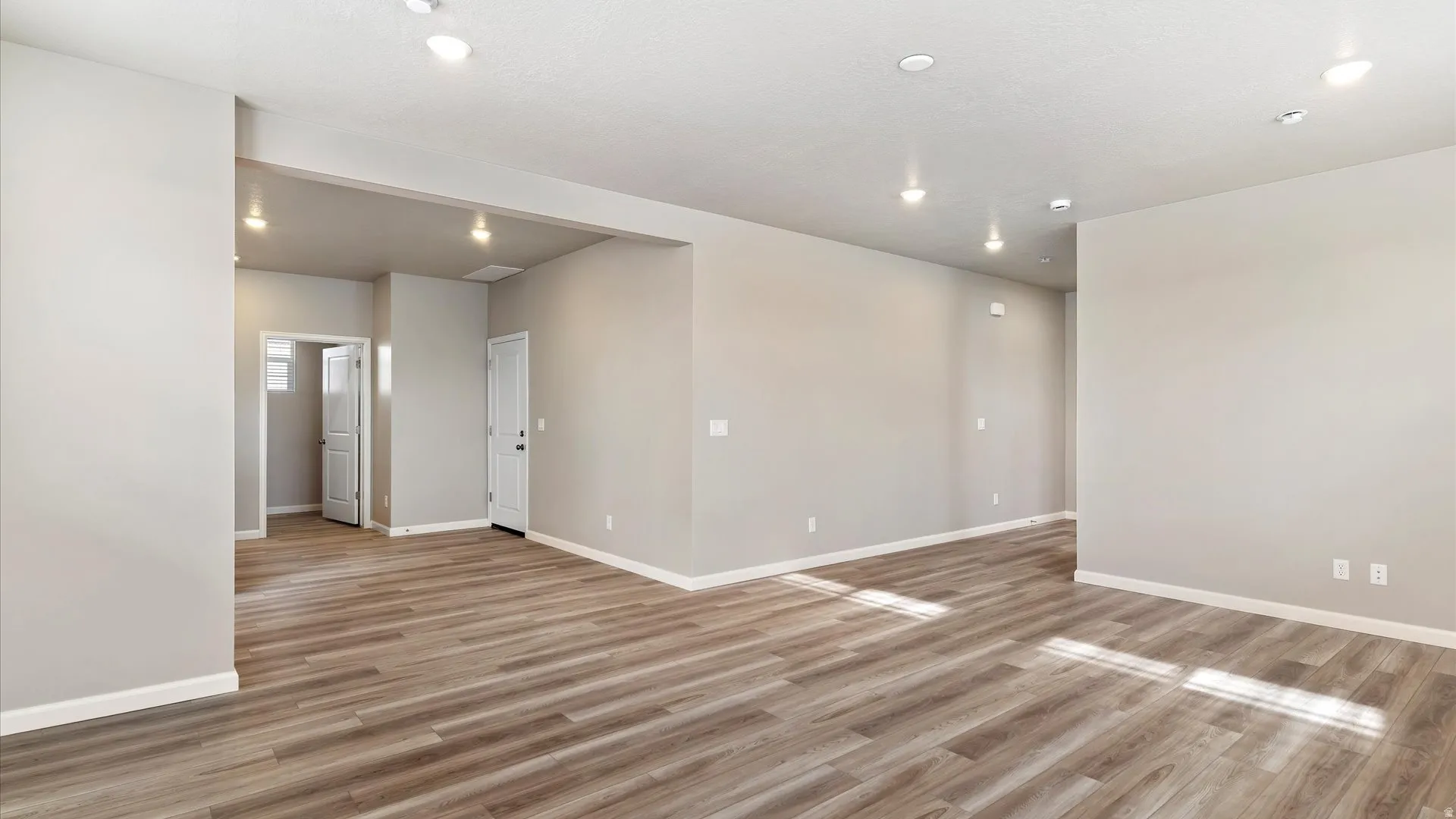 Spacious interior featuring wood-finish flooring, recessed lighting, neutral paint, and white trim