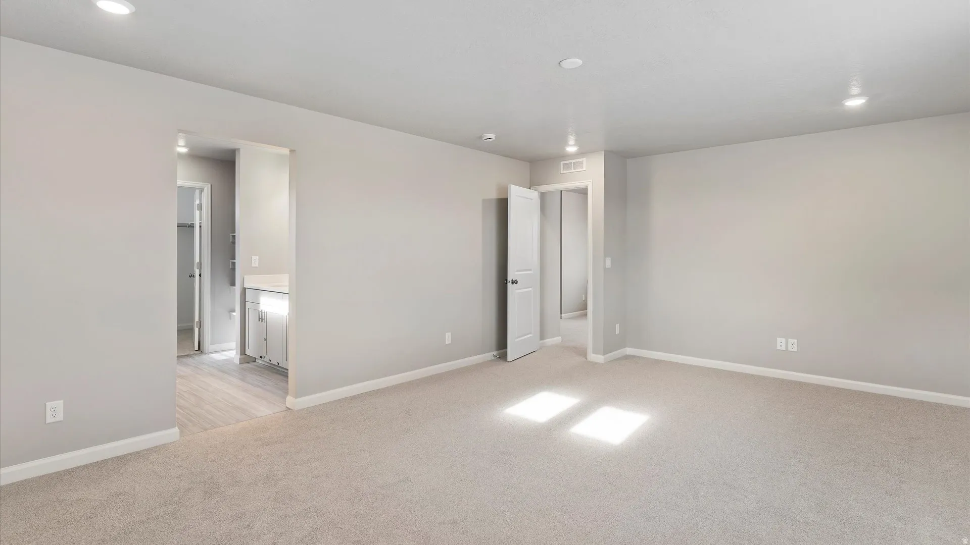 Spacious room featuring neutral carpeting, recessed lighting, and a neutral wall palette