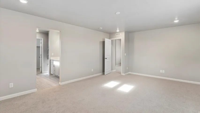 Spacious room featuring neutral carpeting, recessed lighting, and a neutral wall palette