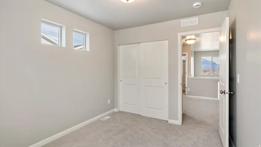 Carpeted room with a double-panel sliding closet door, white baseboards, and two transom windows