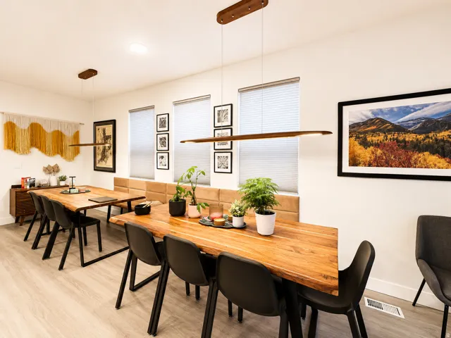 Open-concept dining area featuring light wood-finish flooring, white walls, and modern linear pendant lighting