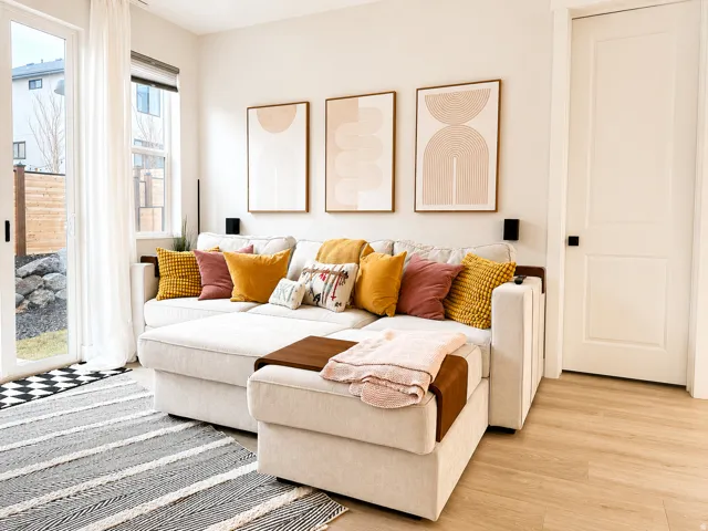 Open-concept living area with light wood-finish flooring, white walls, and a white interior door with black hardware