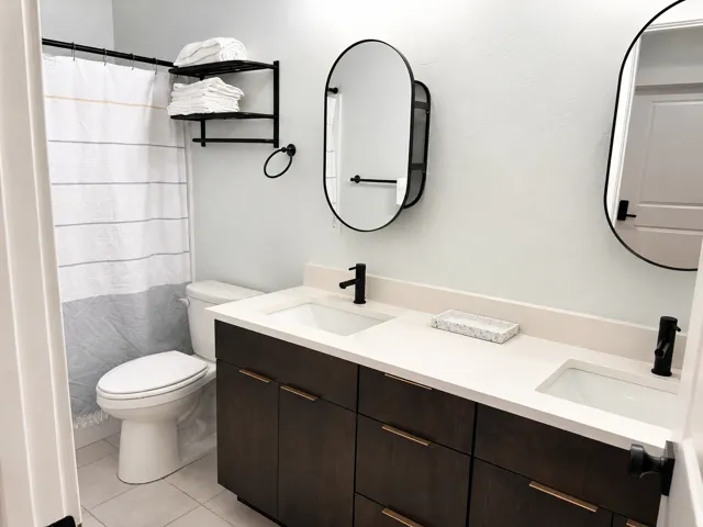 Double vanity featuring dark wood-finish cabinetry, light-toned countertops, and dual undermount sinks with matte black faucets