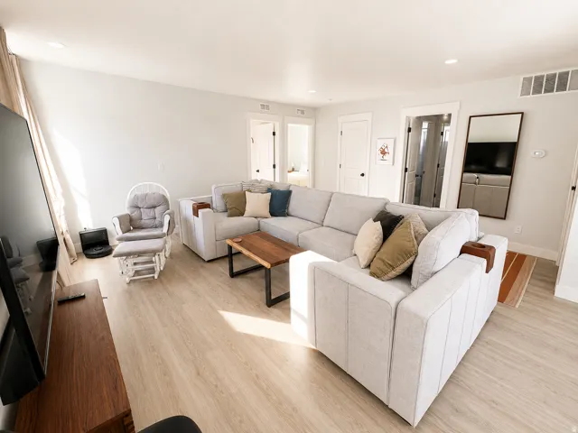 Spacious living area featuring light wood-finish flooring, recessed lighting, and crisp white walls