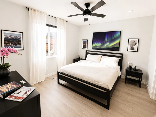 Contemporary bedroom featuring light wood-finish flooring and a ceiling fan with integrated lighting