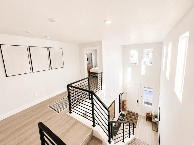 Two-story entryway featuring modern horizontal metal railings, recessed lighting, and light wood-finish flooring