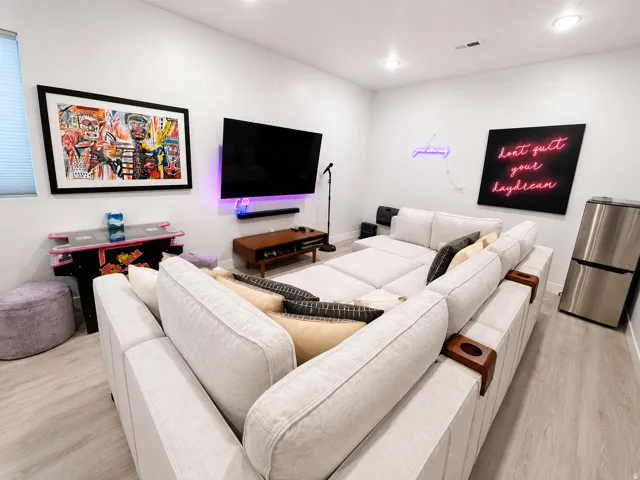Spacious entertainment area featuring light wood-finish flooring, recessed lighting, and ample wall space