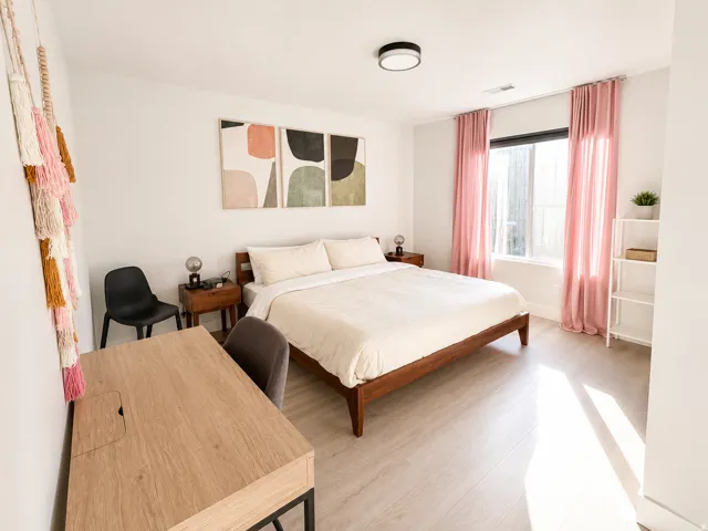 Bright room featuring a single window with curtain rod and neutral-toned wood-finish flooring