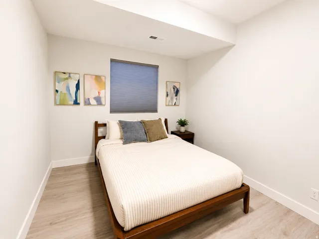 Bedroom featuring light wood-finish flooring, crisp white walls, a recessed ceiling light, and a window with blinds