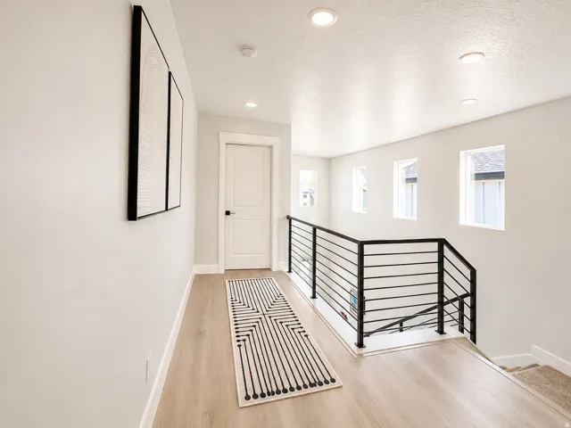 Upper-level hallway featuring wood-finish flooring, recessed lighting, and white walls