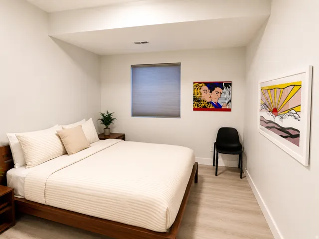 Recessed lighting illuminates this room featuring light wood-finish flooring, a window with a privacy blind, and crisp white walls