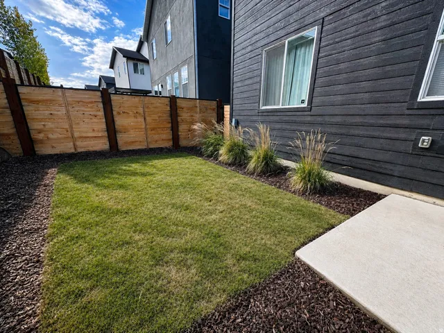 Private Fenced In outdoor space featuring a lush lawn area, concrete patio, and decorative wood chip landscaping