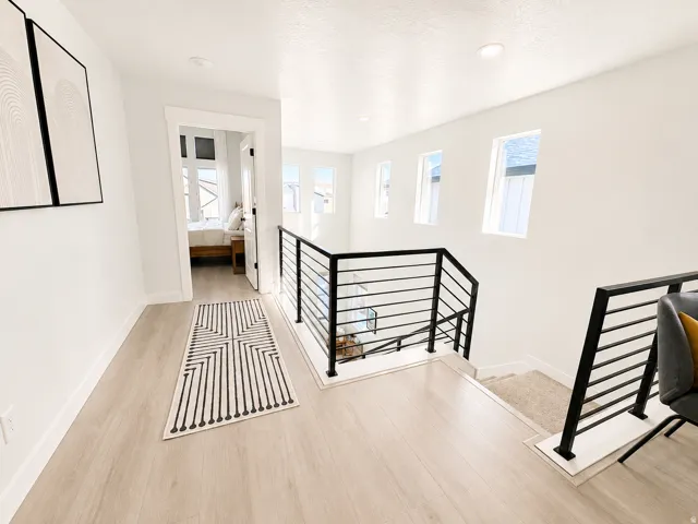 Bright upper-level landing featuring light wood-finish flooring, recessed lighting, and white walls