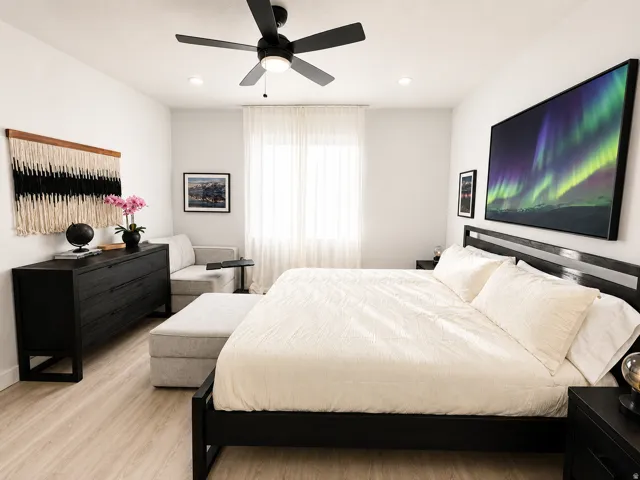 Spacious bedroom featuring light wood-finish flooring, a contemporary ceiling fan with integrated lighting, and recessed lighting