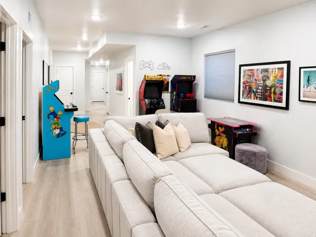 Spacious entertainment area featuring light wood-finish flooring, recessed lighting, and crisp white walls