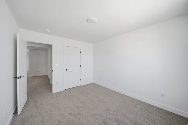Carpeted room featuring white walls and doors with matte black hardware