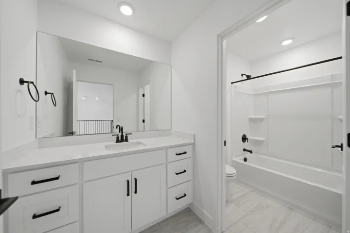 Bathroom featuring a white vanity with extensive countertop space, integrated sink, and matte black fixtures