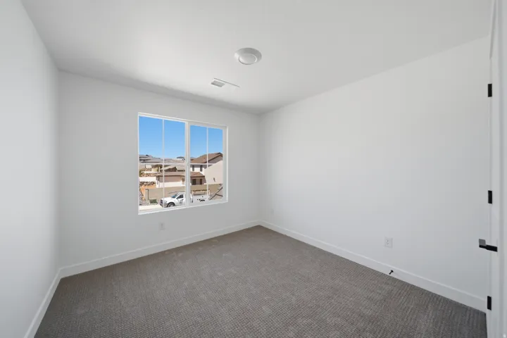 Room featuring a large multi-pane window, neutral-toned carpeting, white walls, and a flush-mount ceiling light