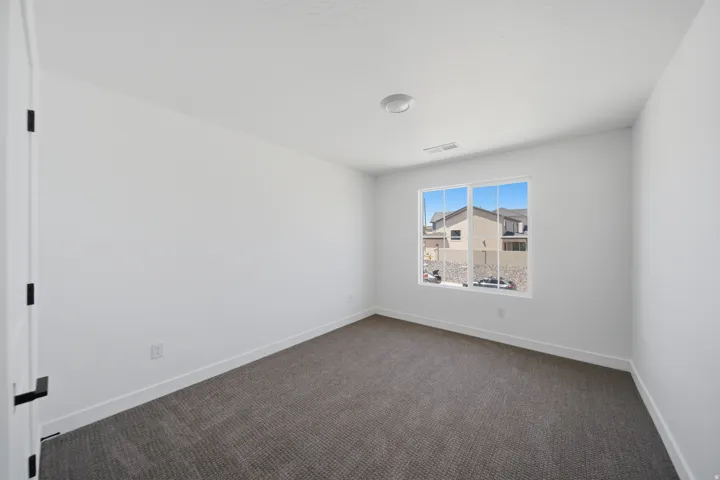 Bright interior space featuring a window with white trim, recessed lighting, white walls, dark gray carpet, and white baseboards
