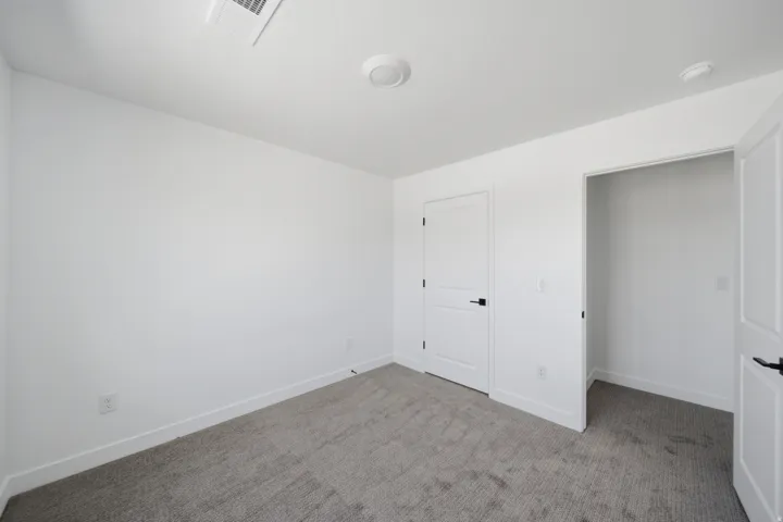Interior room featuring light gray carpet flooring, white walls, and white trim