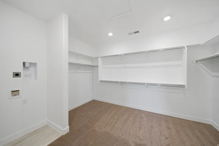 Spacious room featuring extensive wire shelving, recessed lighting, and a blend of carpet and wood-finish flooring