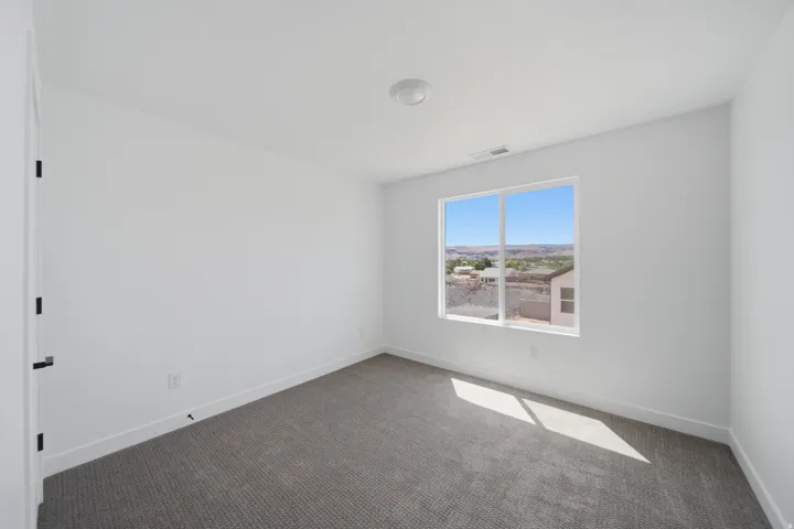 Room featuring a single window, white walls, and gray carpet flooring