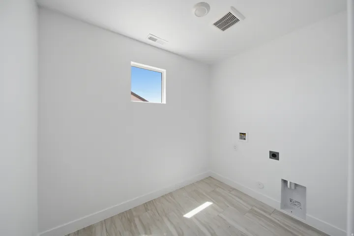 Utility room with a single window, light-toned tile flooring, and white baseboards