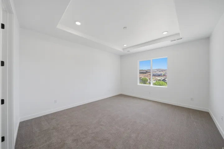 Carpeted room featuring a double tray ceiling with recessed lighting