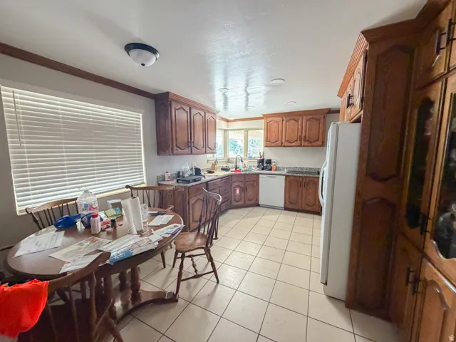 Kitchen featuring wood-finish cabinetry, light-toned tile flooring, and laminate countertops