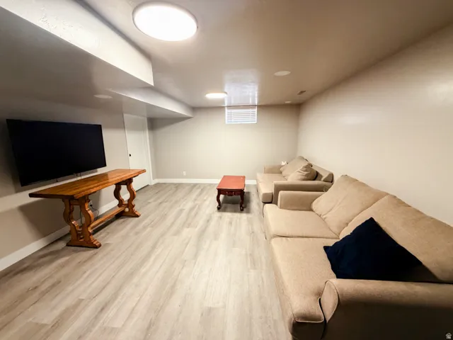 Spacious room featuring light wood-finish flooring, recessed lighting, and a window with horizontal blinds