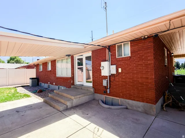 Rear exterior featuring a covered patio, red brick siding, and a concrete patio surface