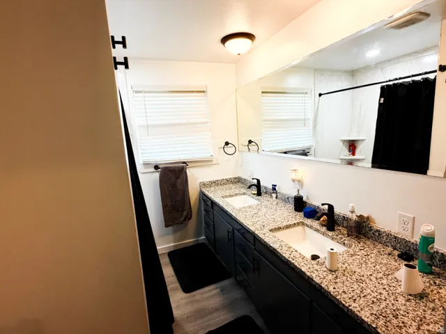 Bathroom featuring a double vanity with granite countertops, undermount sinks, and matte black faucets