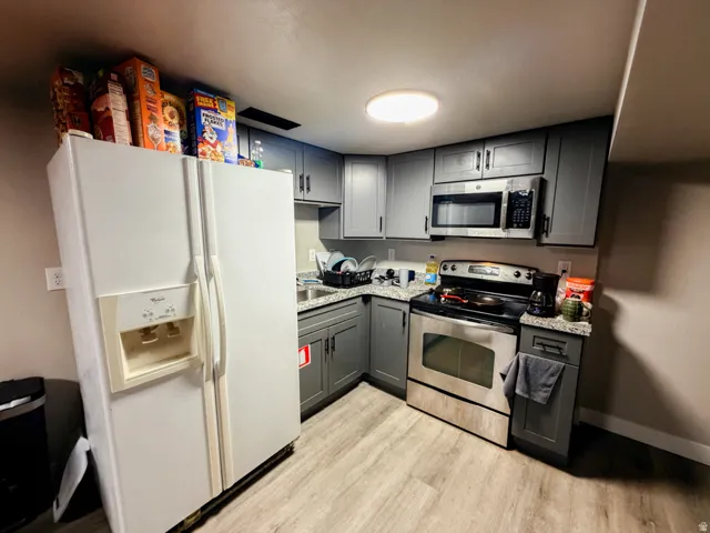 Kitchen featuring gray cabinetry, granite-finish countertops, and wood-finish flooring