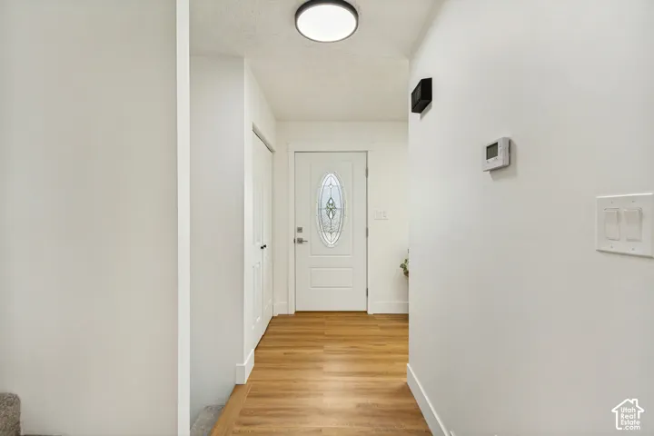 Entryway featuring a white door with decorative glass, LVP flooring, recessed lighting, and a built-in thermostat