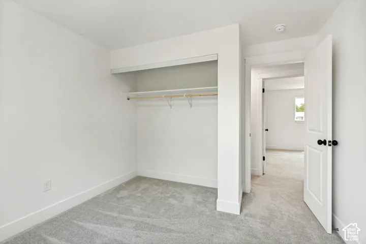 3rd Bedroom featuring light gray carpet, white walls, white trim, and a built-in closet with shelving and a hanging rod