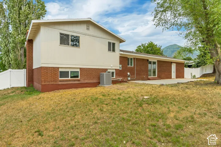 Rear exterior featuring a brick facade, white vinyl siding, and a concrete patio