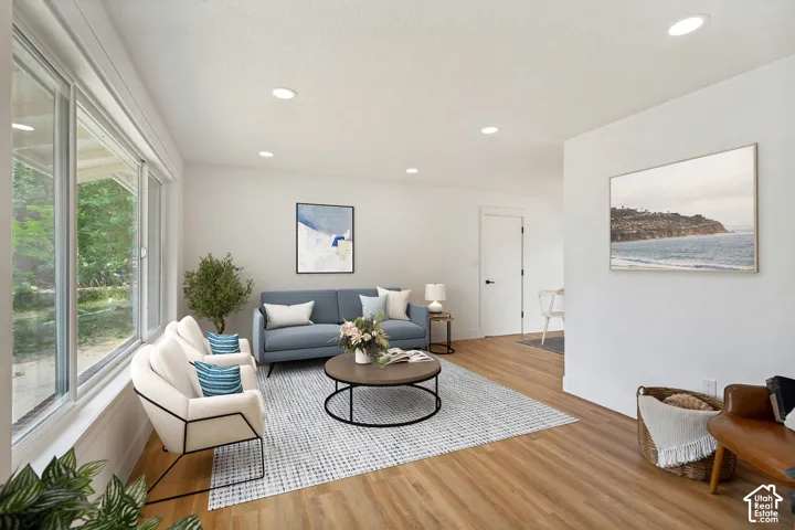 Spacious living area featuring expansive windows, LVP flooring, recessed lighting, and a neutral color palette
